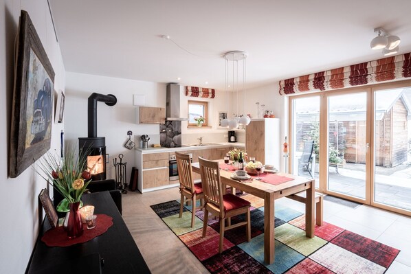 Une cuisine moderne dotée d’une cuisinière intégrée, de meubles de rangement en bois et d’un coin repas avec une table et des chaises.