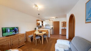 Un salon confortable avec un téléviseur, des meubles en bois, un canapé et un coin repas comprenant une table et des chaises.
