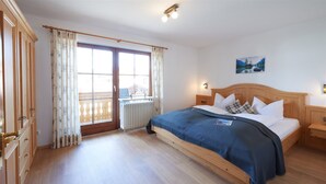 Une chambre à coucher avec un lit en bois, un radiateur, une fenêtre avec des rideaux et un tableau accroché au mur.