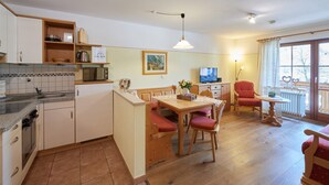 Een kleine keuken met een eethoek, een televisie en een balkon met uitzicht.
