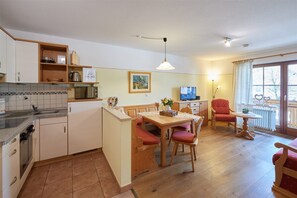 A compact kitchen with a dining area, a TV, and a balcony with a view.