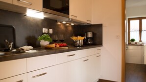 Una cocina moderna con armarios blancos, encimera negra y electrodomésticos de acero inoxidable.