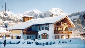 Un bâtiment de style chalet, doté d’un toit en pente, de balcons en bois et d’une enseigne indiquant qu’il s’agit d’un complexe hôtelier de montagne.