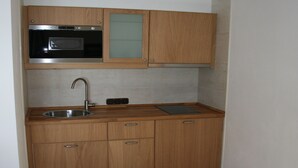 A compact kitchen with wooden cabinets, a stainless steel sink, and a built-in oven. - (2) Ferienwohnung 36m², 2 Personen mit seperaten Schlafzimmer, Du/WC, Balkon (Reit im Winkl)