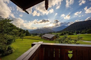 A wooden deck overlooking a green landscape with a mountain in the background.