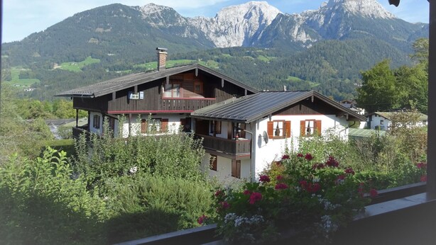 A chalet with a balcony, surrounded by lush greenery and mountains in the background. - Ferienwohnung Nr. 2 Kehlsteinblick, 1 bis 2 Personen, 45 qm, 1 Schlafzimmer, Wohnküche und Balkon (Schönau am Königssee)