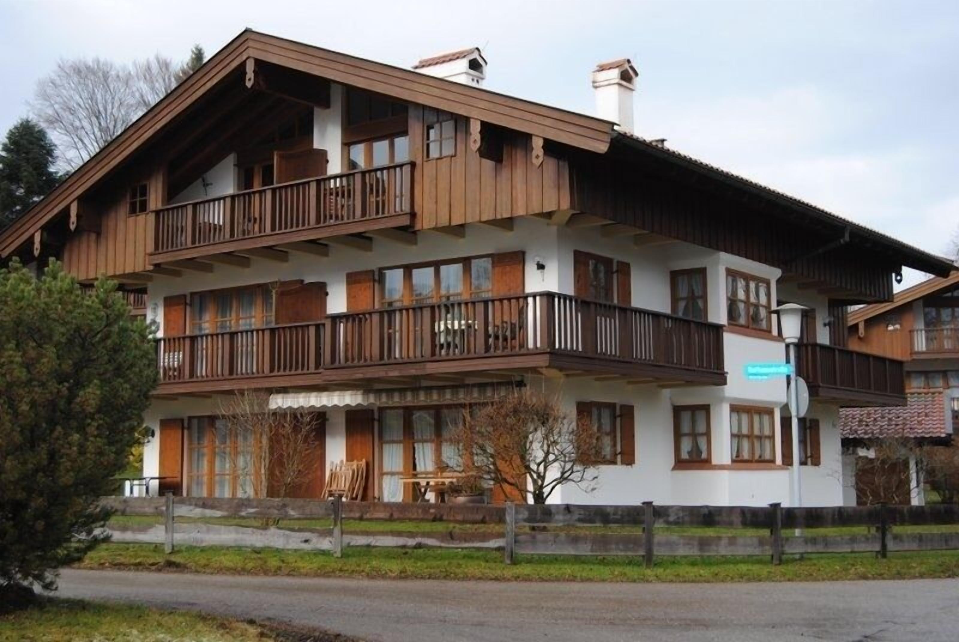 A multi-story wooden building with balconies, large windows, and a visible sign indicating a restaurant.