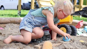 Un enfant joue avec des jouets de plage dans un espace extérieur.