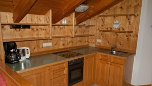 A wooden kitchen with a dishwasher, oven, and a coffee maker on the counter.