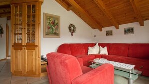 A living room with a red sofa, a glass coffee table, and a wooden cabinet.