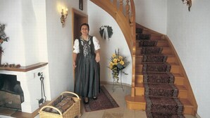 A staircase with a wooden handrail and carpeted steps, a fireplace with a basket, and a wall-mounted light fixture.