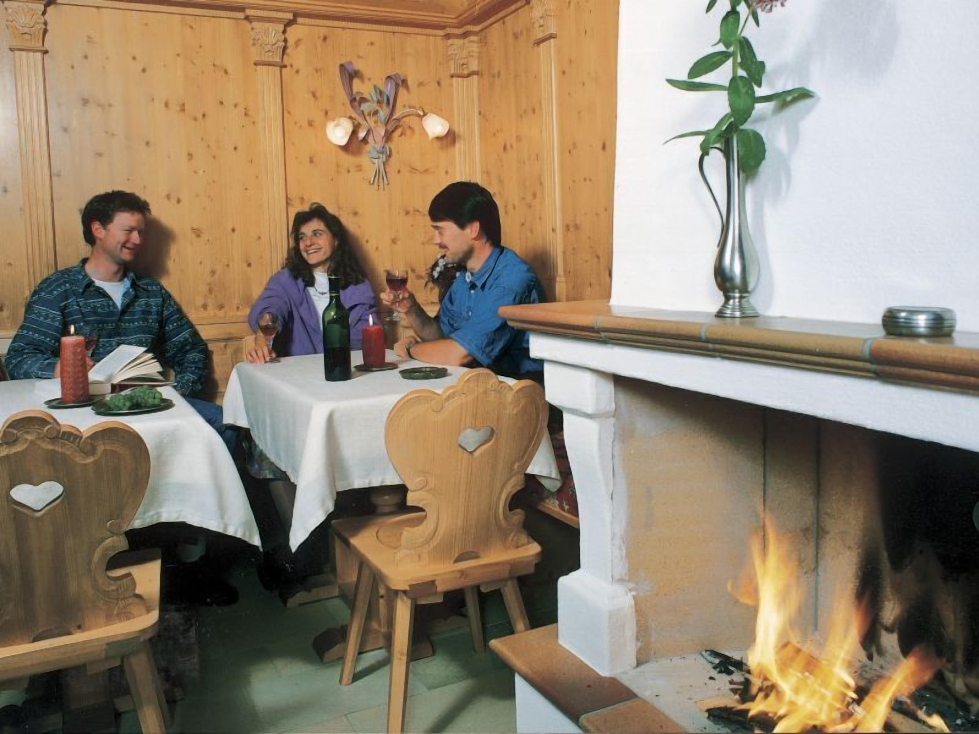 Een gezellig eetgedeelte met houten lambrisering, een open haard en een gedekte tafel voor drie personen.