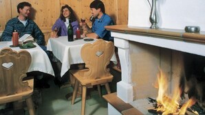 A cozy dining area with wooden paneling, a fireplace, and a table set for three people.