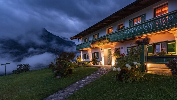 A traditional chalet with a stone pathway leading to the entrance, surrounded by lush greenery and a mountain backdrop. - Ferienwohnung "Beim Sepperl" im Zuhäusl, 1-2 Personen, 40 qm, Dusche/WC, Südbalkon, TV, 1 Schlafzimmer,Nichtraucher (Ramsau bei Berchtesgaden)