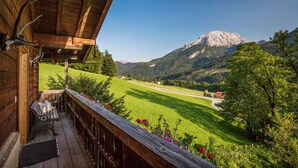 A wooden balcony with a view of a mountain and a green field. - Ferienwohnung "Beim Sepperl" im Zuhäusl, 1-2 Personen, 40 qm, Dusche/WC, Südbalkon, TV, 1 Schlafzimmer,Nichtraucher (Ramsau bei Berchtesgaden)