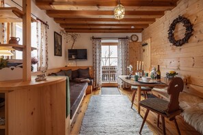 L’intérieur chaleureux d’un chalet avec un plafond en bois, un canapé, une table à manger et une cheminée.
