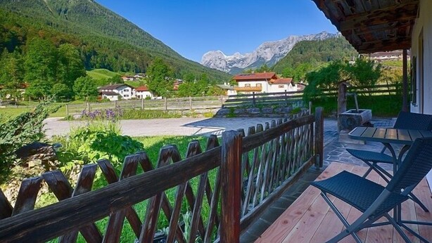 Un terrazzo in legno con vista su una montagna e delle case.