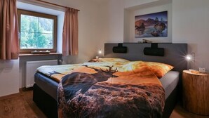 Una camera da letto con un letto, una finestra con tende, un quadro al muro e una lampada da comodino.