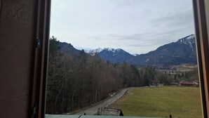 Blick aus einem Fenster auf eine Berglandschaft mit einer Straße und Gebäuden im Tal.
