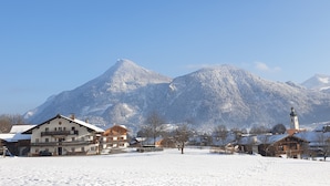 Un pueblo cubierto de nieve con edificios tradicionales y una iglesia, rodeado de montañas.