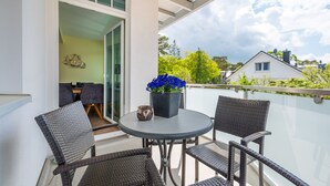 Un balcon avec des fauteuils en osier, une table et un pot de fleurs.