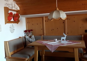 Una mesa de madera para comer con mantel a cuadros, rodeada de bancos acolchados con estampados.