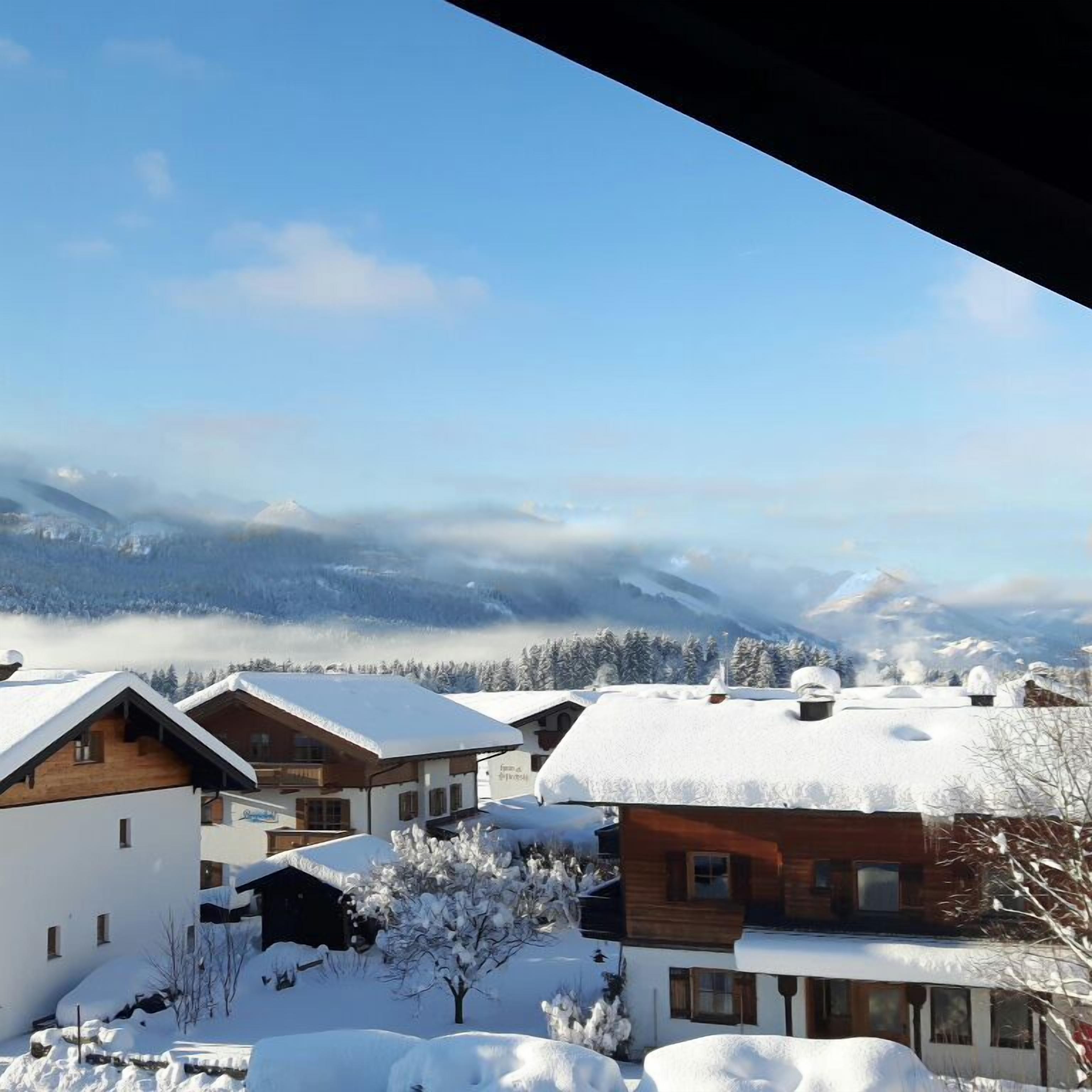 Een besneeuwd dorp met houten huizen en een berg op de achtergrond.