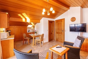 Un salon confortable avec une table à manger, des chaises, un canapé, un téléviseur et des meubles en bois.