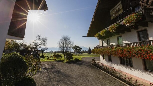 Ein traditionelles Chalet mit Balkon, einem Schotterweg und freiem Blick auf die umliegende Landschaft.