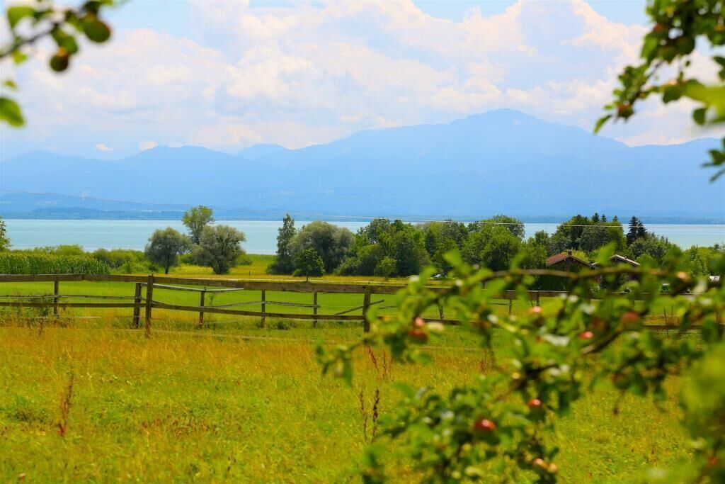 Paesaggio rurale con un lago, montagne e una recinzione di legno.