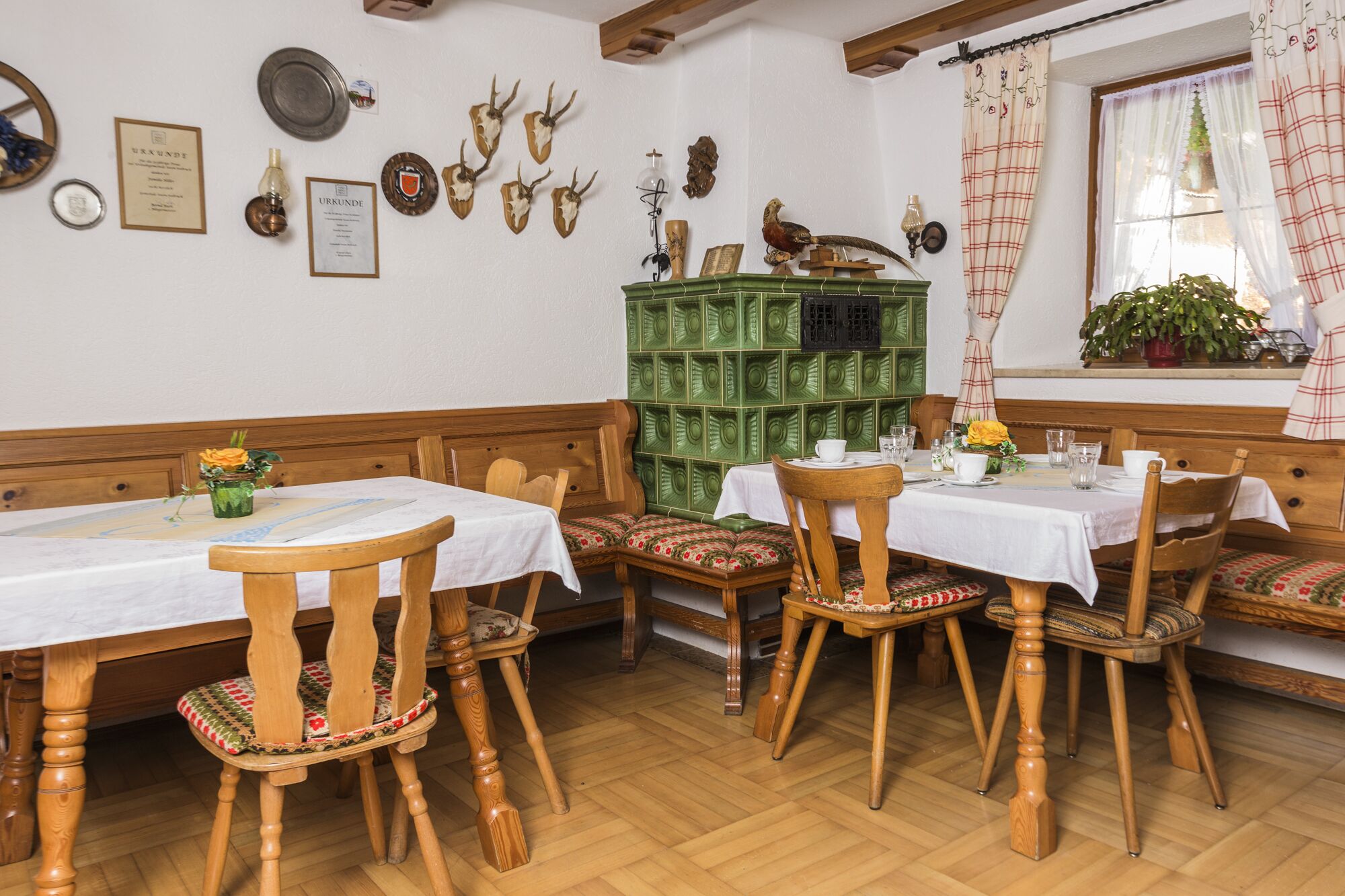 Ett traditionellt värdshus med trämöbler, ett grönt skåp och olika väggdekorationer, inklusive ett hjorttrofé och en fågelbild.