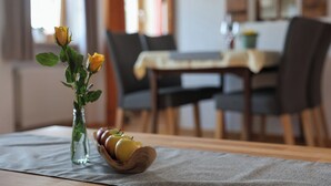 A dining table with chairs, a vase with yellow roses, and a wooden bowl with apples. - Vacation apartment Morgensonne, for 1-4 persons (Berchtesgaden)