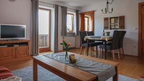 A living room with a TV, dining table, chairs, and a chandelier. - Vacation apartment Morgensonne, for 1-4 persons (Berchtesgaden)