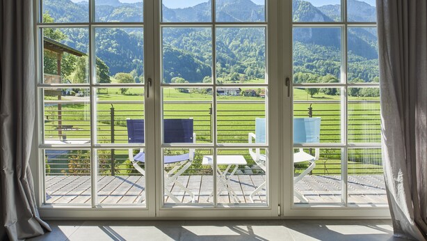 A large window with a view of a green landscape and mountains. - Ferienwohnung II "Kampen" 57 qm, extra Schlafzimmer und Balkon (Aschau im Chiemgau)