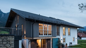 A modern two-story house with a stone facade, large windows, and a balcony. - Ferienwohnung II "Kampen" 57 qm, extra Schlafzimmer und Balkon (Aschau im Chiemgau)