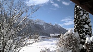 A snow-covered landscape with a mountain in the background and a building with multiple windows. - Apartment Anemone for 3 persons, balcony, 1 bedroom, 46 m² (Inzell)