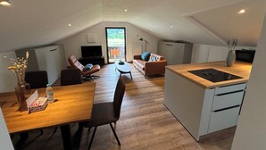 A modern loft apartment with a dining area, living room, and kitchenette. - Apartment Anemone for 3 persons, balcony, 1 bedroom, 46 m² (Inzell)