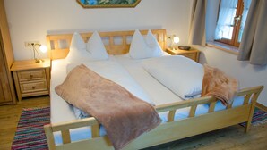 Una cama bien hecha con ropa de cama blanca y marrón, un cabecero de madera y dos mesitas de noche con lámparas.