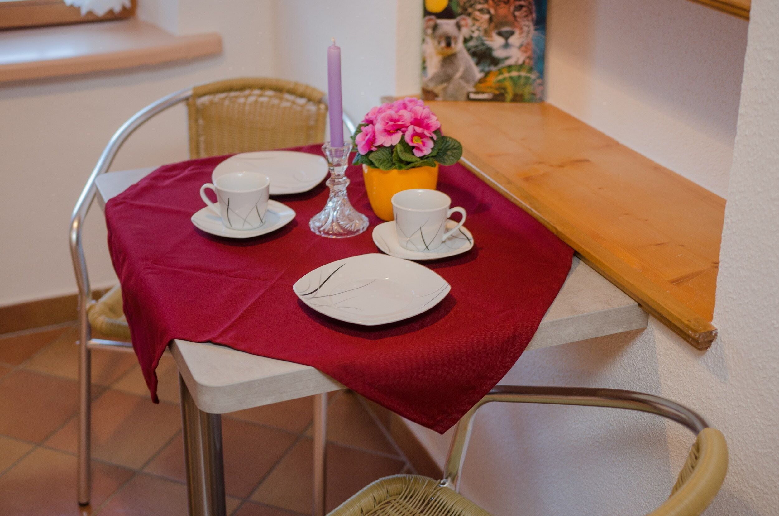 Ett matbord dukat med vita tallrikar, koppar och en vas med rosa blommor.