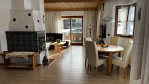 Een ruime woonkamer met een open haard, een eethoek met een tafel en stoelen, en een zithoek.