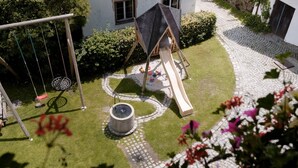 Een kinderspeelplaats met een schommel, glijbaan en een klein waterattractie.