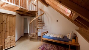 Slaapkamer in een loft met een houten trap, een stapelbed en een houten garderobe.