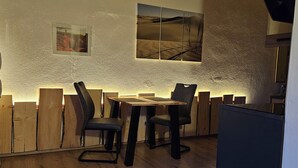 Un coin repas avec une table et des chaises en bois, un mur à texture et des œuvres d’art encadrées.
