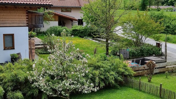 Une maison de campagne avec un toit en tuiles, entourée d’une végétation luxuriante et située dans un paysage vallonné.