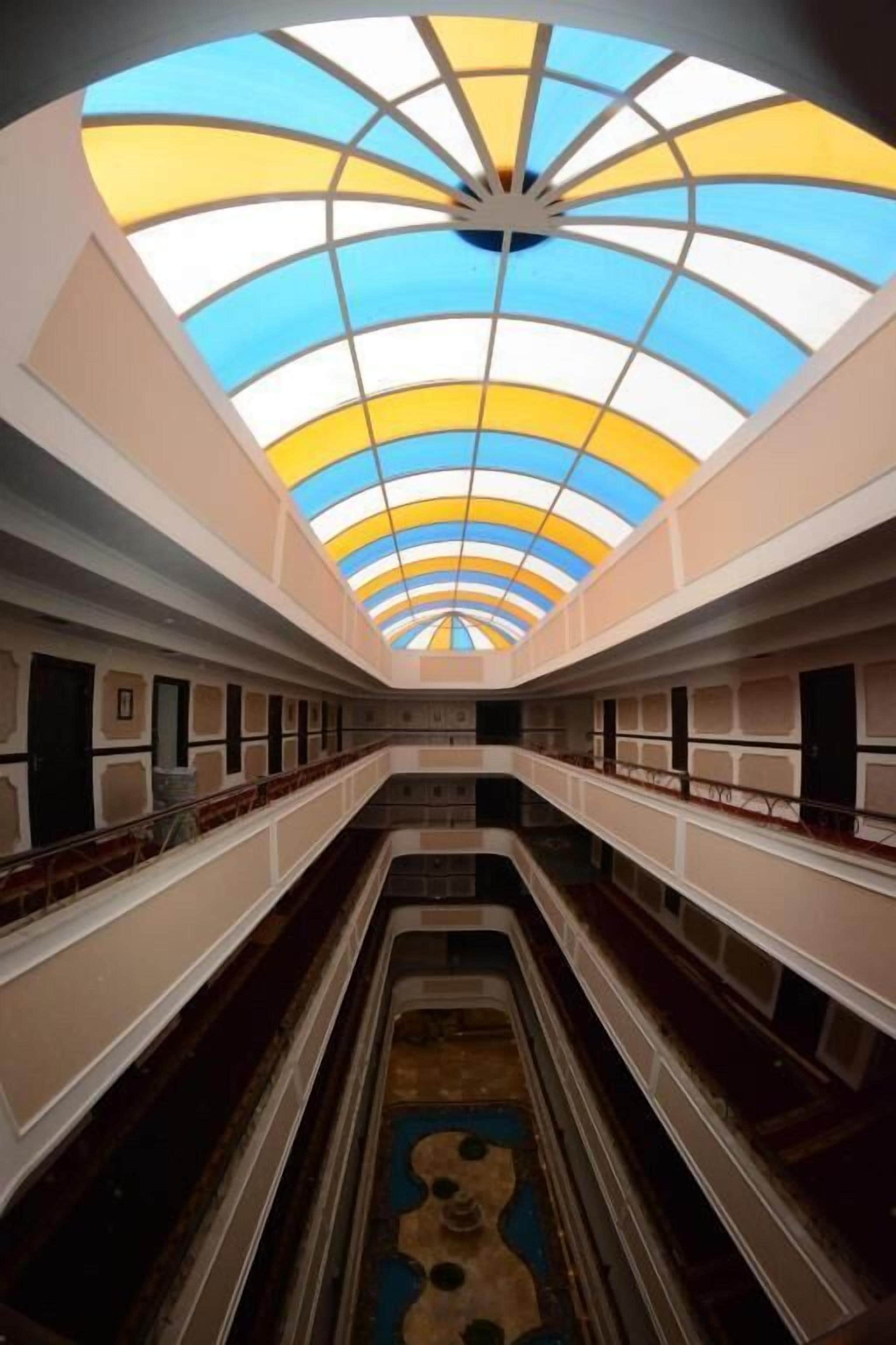Un atrium à plusieurs niveaux, doté d’un escalier central, d’une verrière au motif radial et d’un sol à motifs.