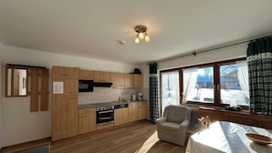 Una cucina moderna con mobili in legno, un tavolo da pranzo e vista sull'esterno tramite un'ampia finestra.