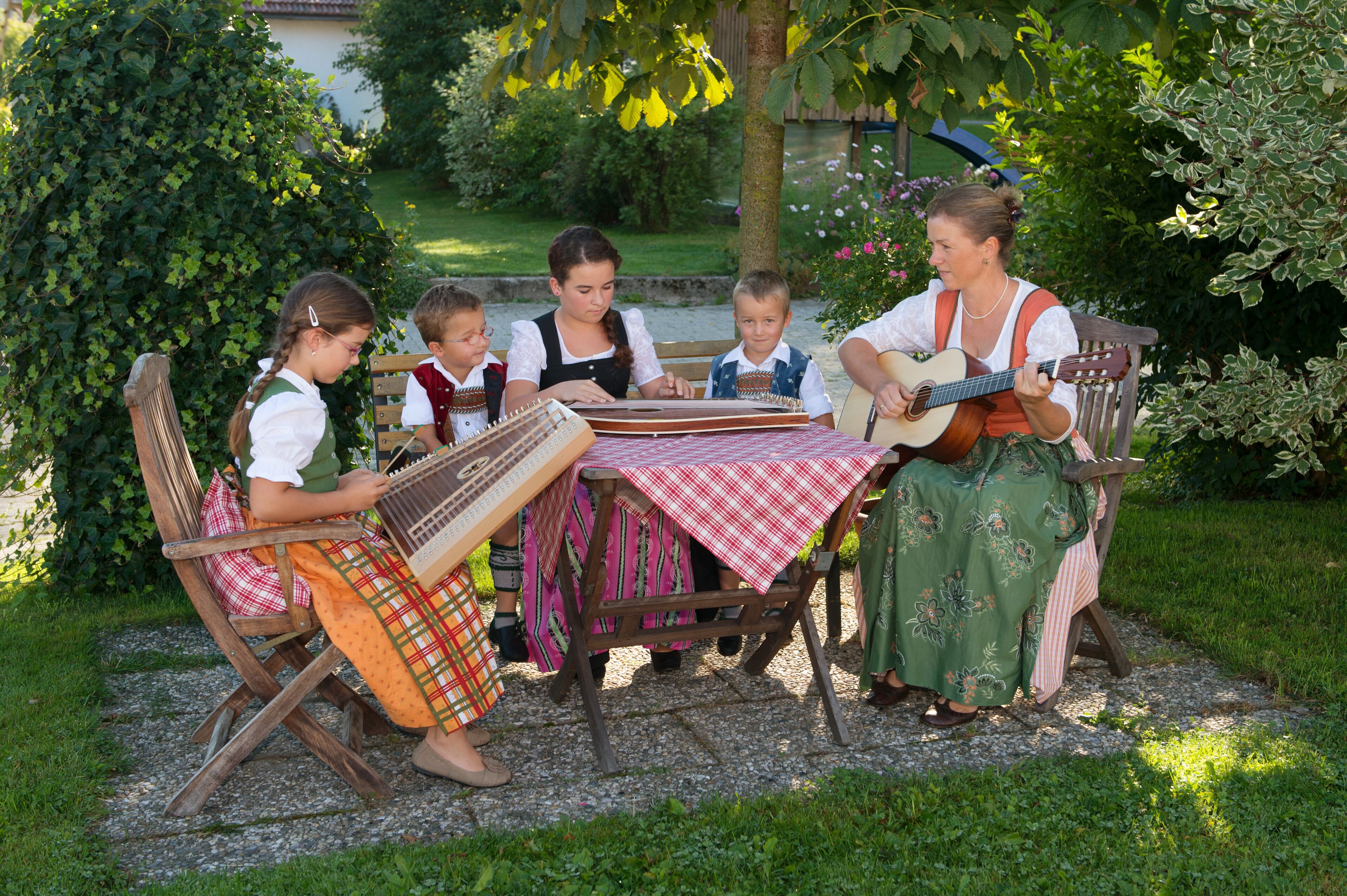 Een groep mensen zit buiten aan een tafel en speelt traditionele instrumenten.