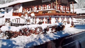 Un bâtiment de style alpin traditionnel, doté d’un toit en pente, de plusieurs balcons et d’une façade recouverte de neige.