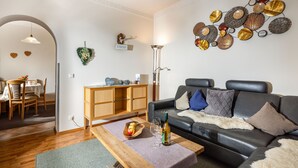 A living room with a wooden coffee table, a sofa with decorative pillows, a wall art piece, and a dining area with a table and chairs. - Vacation apartment Wiesentraum, for 1-2 persons (Berchtesgaden)