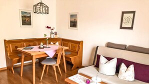 A cozy room with a wooden dining table, benches, a sofa, and a small table with a candle. - Ferienwohnung II 65 qm°, mit zwei extra Schlafzimmer mit Süd-Balkon (Aschau im Chiemgau)
